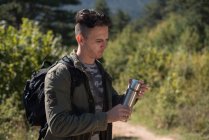 Wanderer steht im Wald und öffnet eine Wasserflasche — Stockfoto