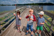 Three children standing on a dock holding a catch of fish, United States — Stock Photo