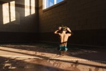 Junge steht im Schwimmbad und justiert seine Schwimmbrille — Stockfoto