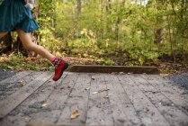 Дівчина біжить через маленький пішохідний міст, вид збоку — стокове фото