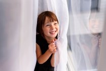 Дівчина ховається за шторою сміється — стокове фото