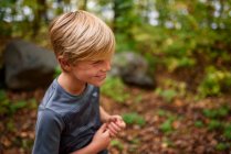 Sonriente niño de pie en el bosque a principios de otoño, Estados Unidos - foto de stock