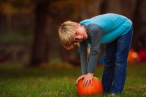 Boy in a garden bending over to pick up a pumpkin, United States — Stock Photo