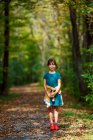 Усмішка дівчинка стоїть на стежці в лісі, об'єднані держави — стокове фото