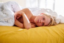 Boy lying in bed waking up — Stock Photo