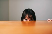 Девушка прячется за столом — стоковое фото