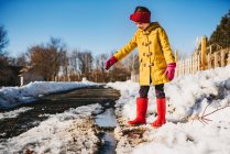 Mädchen steht an einer Pfütze aus schmelzendem Schnee, USA — Stockfoto
