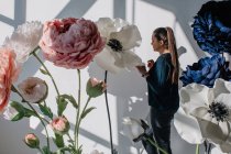Portrait d'une femme debout à côté de fleurs artificielles géantes — Photo de stock