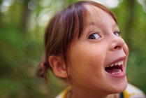 Portrait of a smiling girl standing outdoors pulling funny faces, United States — Stock Photo