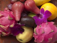 Tropical fruits and flower arrangement — Stock Photo