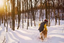 Boy walking through a forest in the snow with his dog, United States — Stock Photo