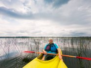 Смиллинг пожилой женщины на байдарке на озере, США — стоковое фото