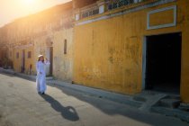 Woman walking down the street wearing traditional clothing, Hoi An, Vietnam — Stock Photo
