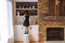 Girl standing on a stool putting up Halloween ghost decorations — Stock Photo