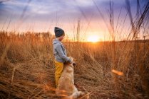 Boy standing in a field with his golden retriever dog, United States — Stock Photo
