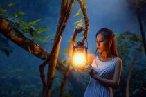 Donna in piedi nella foresta con una lanterna in mano, Thailandia — Foto stock