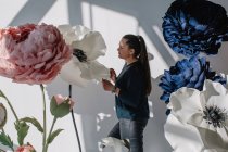 Портрет женщины, стоящей рядом с огромными искусственными цветами — стоковое фото