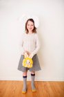 Portrait of a smiling girl wearing bunny ears holding a bunny bag — Stock Photo