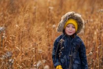 Портрет улыбающейся девушки, стоящей в поле и жующей кусок длинной травы, США — стоковое фото