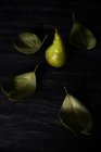 Крупним планом вид на грушу на столі, оточений листям — стокове фото