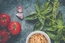 Fresh basil with penne pasta, tomatoes and garlic — Stock Photo