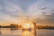 Éclaboussures d'eau dans la rivière dans la scène du coucher du soleil — Photo de stock