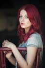 Retrato de uma mulher bonita com cabelo vermelho sentado em uma cadeira — Fotografia de Stock
