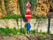 Chica de pie bajo una señal de tráfico en la calle, Abruzos, Italia - foto de stock