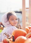 Portrait of a smiling girl with windswept hair standing next to pumpkins, Washington, USA — Stock Photo