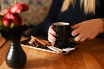 Жінка сидить за столом насолоджуючись чашкою кави — стокове фото