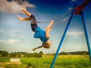 De cabeça para baixo menina balançando em um balanço em um playground, Polônia — Fotografia de Stock