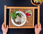 Overhead view of a woman holding a tray with Vietnamese Pho soup — Stock Photo