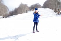 Chica sonriente de pie en la nieve, Italia - foto de stock