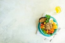 Ciotola sana per la colazione con quinoa, pollo, verdure e spezie sullo sfondo di un tavolo. vista dall'alto — Foto stock