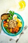 Gesunde Frühstücksschale mit Quinoa, Huhn, Gemüse und Gewürzen auf dem Hintergrund eines Tisches. Ansicht von oben — Stockfoto