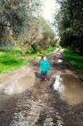 Chica caminando por un sendero fangoso en el campo, Italia - foto de stock