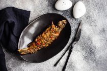 Смажений лосось з овочами та спеціями на чорній тарілці — стокове фото