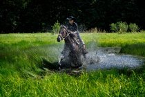 Retrato de mulher montando através de um lago na paisagem rural, Polônia — Fotografia de Stock