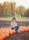 Chica sonriente sentada en un parche de calabaza en otoño, Washington, EE.UU. - foto de stock