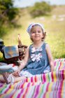 Ragazza sorridente seduta su una coperta da picnic nel parco, Bulgaria — Foto stock