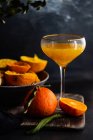 Fresh orange juice with lemon and cinnamon on a black background. — Stock Photo
