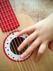 Primo piano della mano di un bambino che suona la chitarra — Foto stock