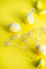 Ovos de Páscoa e flores em um fundo amarelo — Fotografia de Stock