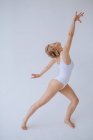 Гимнастка в белом трико танцует в студии — стоковое фото