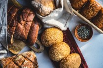 Vista aérea de una variedad de panecillos y panes de pan con semillas de sésamo - foto de stock