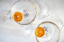 Overhead view of two glasses of champagne with slices of dried orange — Stock Photo