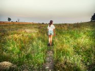 Visão traseira de uma garota andando no campo, Polônia — Fotografia de Stock