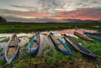 Fila de barcos de pesca ancorados no lago Lebo ao pôr do sol, Sumbawa, Indonésia — Fotografia de Stock