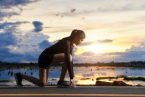 Woman getting ready to run along a lakeside road, Thailand — Stock Photo