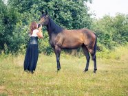Mujer de pie en un campo besando a un caballo, Polonia - foto de stock